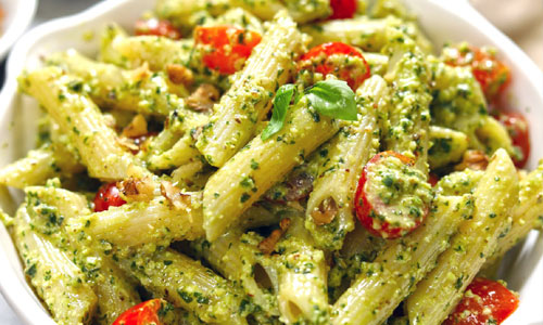A freshly tossed Pesto Basil Pasta topped with cherry tomatoes